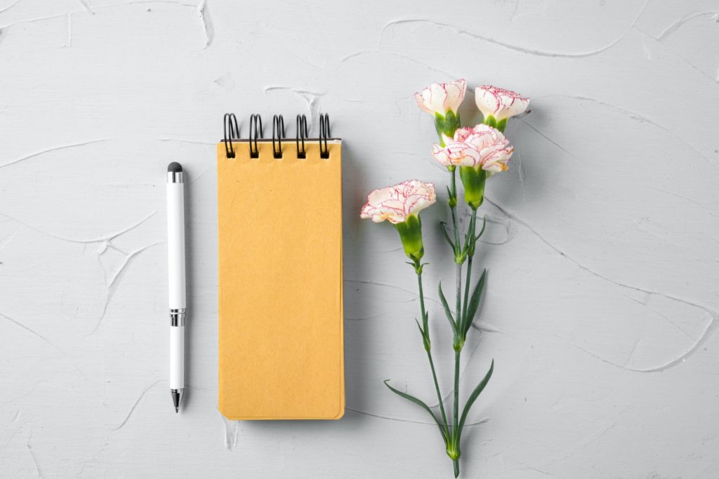 Blank notepad page with flower branch, top view